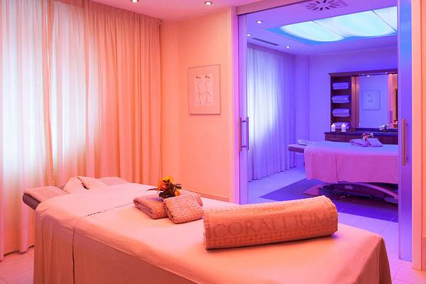 Spa-Behandlungsraum im Lopesan Villa del Conde Resort mit pinker Beleuchtung und zwei Liegen.