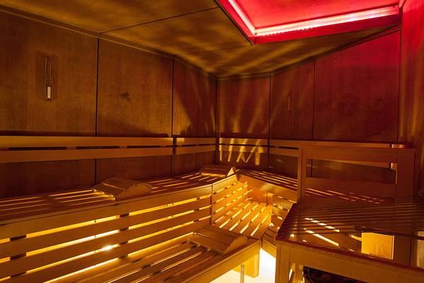 Innenansicht der Sauna im Lopesan Villa del Conde Resort & Thalasso mit Holzbänken und roter Beleuchtung.
