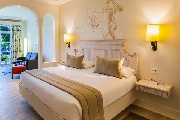 Innenansicht eines Hotelzimmers im Lopesan Villa del Conde Resort & Thalasso mit Bett, Sesseln, Schreibtisch und Panoramafenstern.