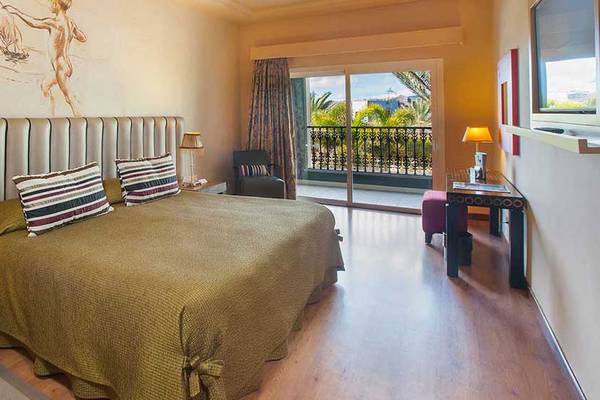 Schlafzimmer im Lopesan Villa del Conde Resort & Thalasso mit einem Bett, Lampen und einem Balkon.