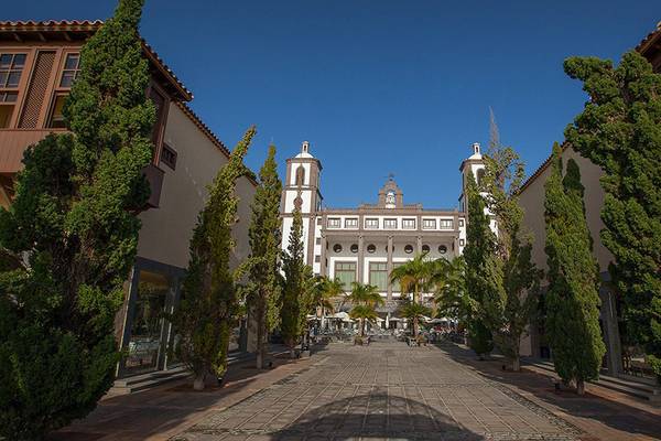 Eingang zum Lopesan Villa del Conde Resort & Thalasso mit hohen Bäumen und gepflastertem Weg