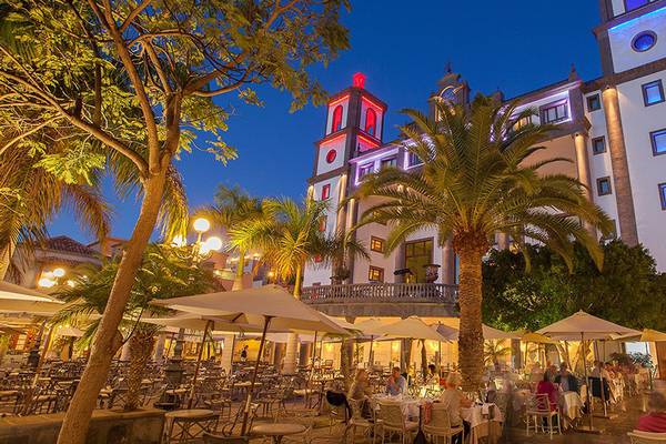 Abendansicht des Lopesan Villa del Conde Resorts mit beleuchtetem Gebäude und Gästen in einem Außenbereich