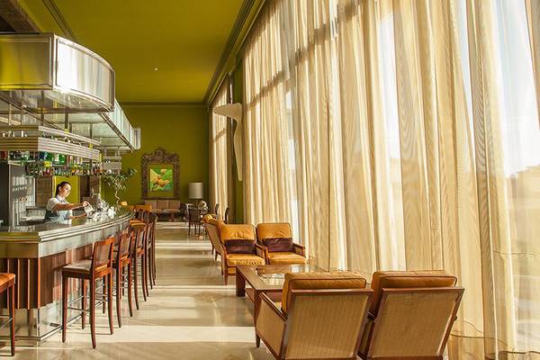 Innenansicht der Bar im Lopesan Villa del Conde Resort & Thalasso mit einer Barkeeperin, die Getränke serviert.