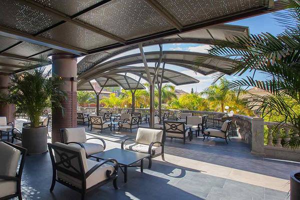 Terrasse des Lopesan Villa del Conde Resort & Thalasso mit Sonnenschirmen und Möbeln