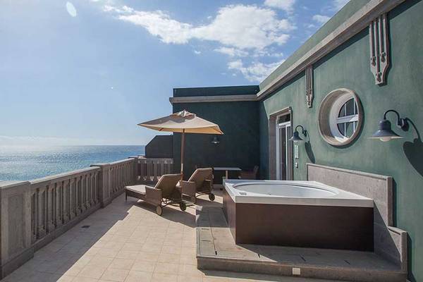 Terrasse mit Meerblick im Lopesan Villa del Conde Resort mit Jacuzzi, Sonnenliegen und Sonnenschirm.