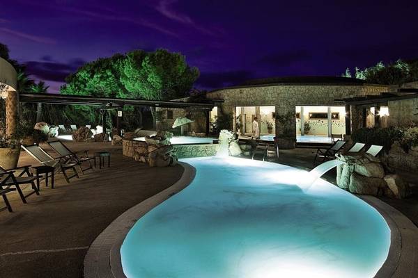 Außenpool des Marinedda Hotel Thalasso & Spa bei Nacht mit Lounge-Stühlen und Pflanzen.