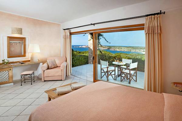 Schlafzimmer im Marinedda Hotel Thalasso & Spa mit Meerblick, einem Bett, einem Tisch, Stühlen und einem Balkon.