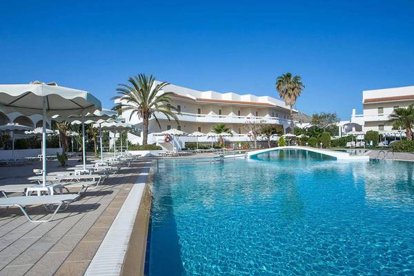 Ein großer Swimmingpool am Niriides Beach Hotel mit weißen Sonnenliegen und Sonnenschirmen.
