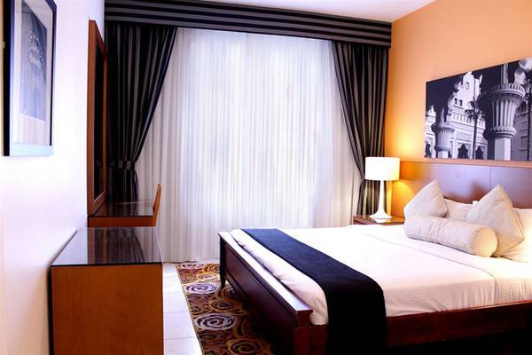 Schlafzimmer im Golden Sands Hotel Apartments mit Doppelbett, Lampen und Wanddekoration.
