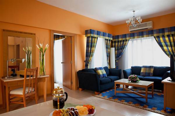 Wohnzimmer im Golden Sands Hotel Apartments mit zwei Sofas, Tisch, Teppich und Dekoration.