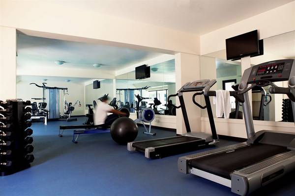 Fitnessstudio im Golden Sands Hotel Apartments mit Trainingsgeräten und Spiegeln.