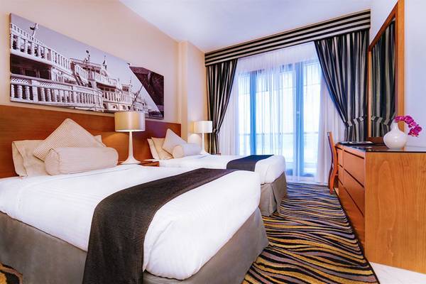 Doppelzimmer im Golden Sands Hotel Apartments mit zwei Betten, Lampen und Panoramafenstern.