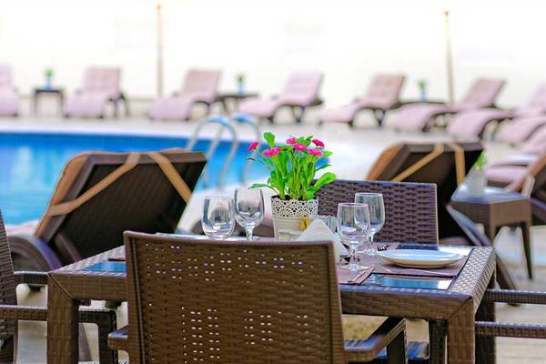 Gartentisch mit Blumen und Strandliegen am Pool des Golden Sands Hotel Apartments
