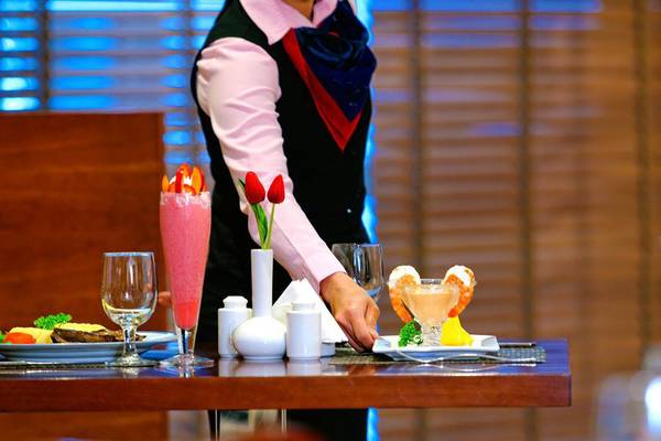 Serviererin im Restaurant des Golden Sands Hotel Apartments, die ein Essen serviert.