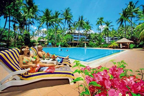 Zwei Personen, die sich an einem Swimmingpool im Freien entspannen, im Prama Sanur Beach Bali Hotel.