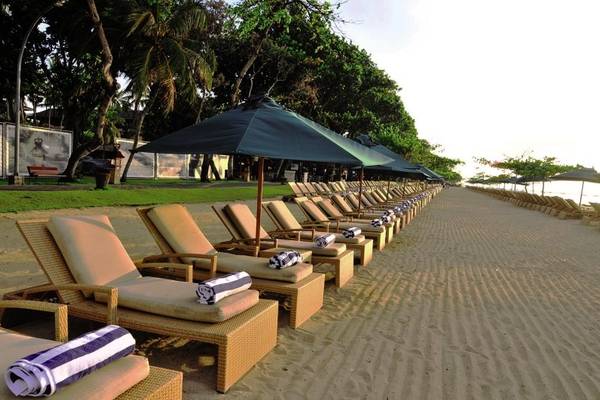 Reihe von Liegestühlen am Strand des Prama Sanur Beach Bali Hotels mit Sonnenschirmen und Handtüchern