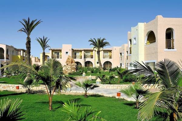 Außenbereich des VOI Praia De Chaves Resort mit Gebäuden, Palmen und Rasen.