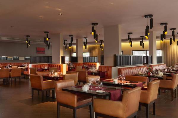Innenansicht des Restaurants im Melia Dunas Beach Resort & Spa mit gepolsterten Stühlen und Tischen.