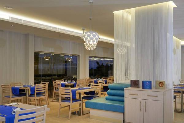 Innenansicht des Restaurants im Melia Dunas Beach Resort & Spa mit modernen Möbeln und blauen Akzenten.
