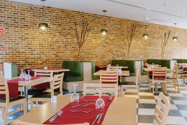Innenansicht des Restaurants im Melia Dunas Beach Resort & Spa mit grünen und weißen Sitzecken und gemustertem Boden.