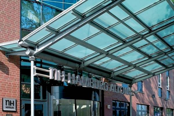 Eingang des NH Hamburg Altona Hotels mit Glasüberdachung und gepflegtem Eingangsbereich.