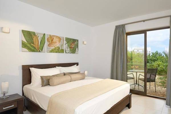 Schlafzimmer im Melia Dunas Beach Resort & Spa mit Bett, Nachttischen, Fernseher und Terrassentür.
