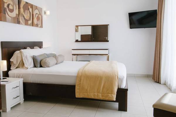 Schlafzimmer im Melia Dunas Beach Resort & Spa mit einem Doppelbett, Nachttischen, Lampen, einem Kleiderschrank und Wanddekoration.