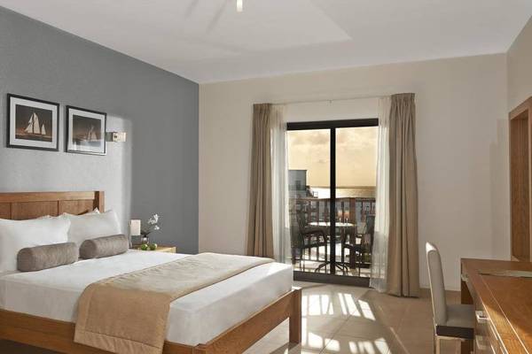 Innenansicht eines Schlafzimmers im Melia Dunas Beach Resort mit Bett, Nachttischen und Balkon.