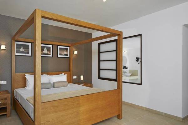 Ein Schlafzimmer im Melia Dunas Beach Resort & Spa mit einem großen Bett, Holzmöbeln und einer modernen Einrichtung.