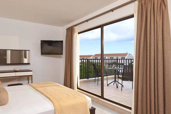 Ein Zimmer im Melia Dunas Beach Resort mit Balkon, Fernseher und Tisch mit Stühlen draußen.