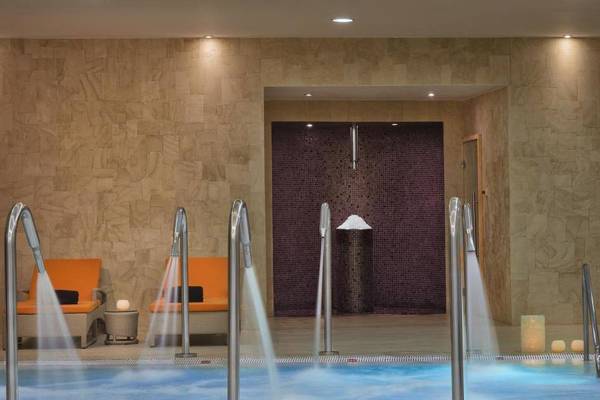 Innenpoolbereich des Melia Dunas Beach Resort & Spa mit Wasserstrahlliegen und Loungesesseln.
