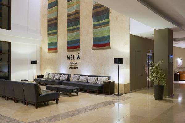 Lobby des Melia Dunas Beach Resort & Spa Hotels mit Sofas, Lampen und einer Pflanze.