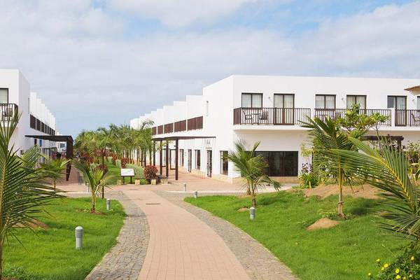 Außenbereich des Melia Dunas Beach Resort & Spa mit weißen Gebäuden und gepflastertem Weg.