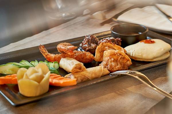 Ein Teller mit verschiedenen Gerichten im Mayia Exclusive Resort & Spa, einschließlich Garnelen, Frühlingsrollen und gebratenem Hühnchen.