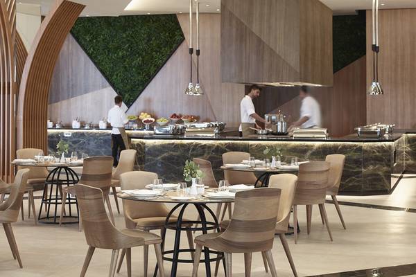 Innenraum des Mayia Exclusive Resort & Spa mit gepflegten Tischen und Stühlen, Mitarbeitern hinter der Theke.