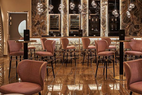 Bar Bereich im Mayia Exclusive Resort & Spa mit rosa Stühlen und einer Theke.