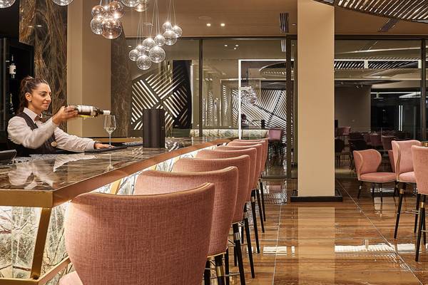 Rezeptionistin schenkt Wein ein in der Bar des Mayia Exclusive Resort & Spa