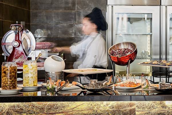 Buffet-Counter im Mayia Exclusive Resort & Spa mit verschiedenen Speisen und einer Köchin im Hintergrund.