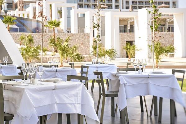 Restaurant-Terrasse im Mayia Exclusive Resort & Spa mit weißen Tischen und Stühlen.