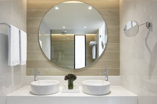Badezimmer im Mayia Exclusive Resort & Spa mit zwei Waschbecken, einem großen Spiegel und Holzakzenten.