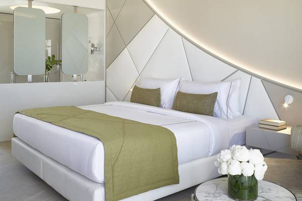 Ein elegantes Schlafzimmer im Mayia Exclusive Resort & Spa mit weißem Bett, grüner Decke und Marmortisch.
