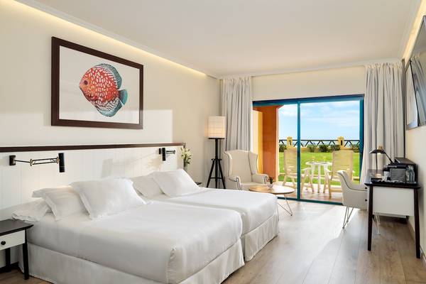 Innenansicht eines Doppelzimmers im H10 Playa Esmeralda Hotel mit zwei Betten und einem Balkon.