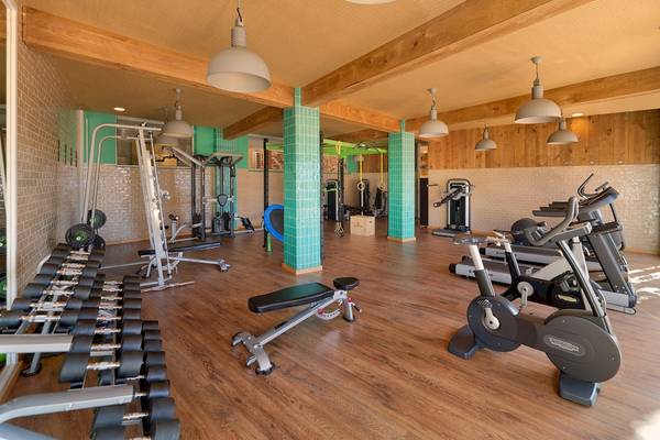 Fitnessstudio im H10 Playa Esmeralda Hotel mit verschiedenen Geräten und Holzboden.