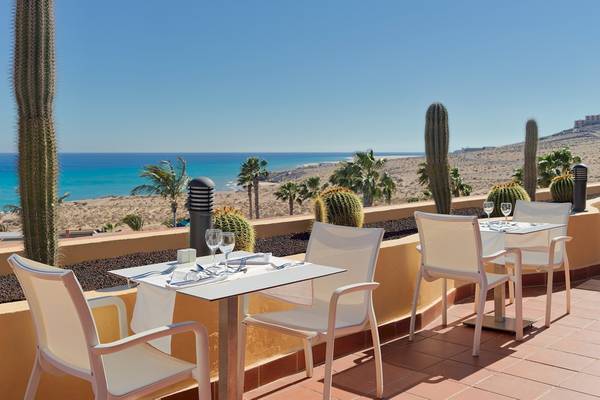 Terrasse im H10 Playa Esmeralda Hotel mit Blick auf das Meer und Kakteen.