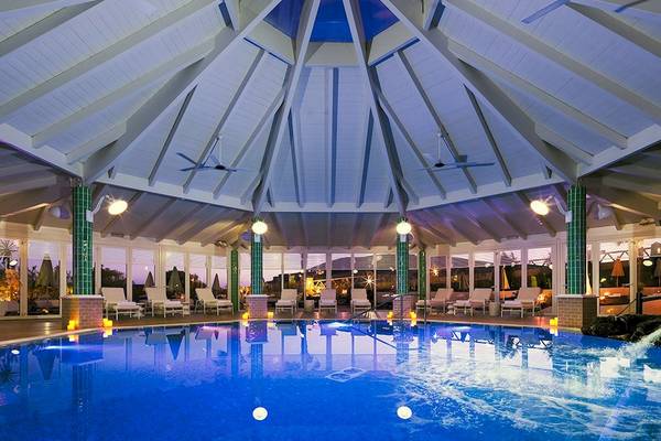 Innenpool im H10 Playa Esmeralda Hotel mit blauem Wasser und weißen Liegestühlen.