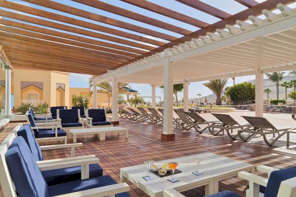 Terrasse des H10 Playa Esmeralda Hotels mit Lounge-Stühlen und einem Tisch mit Getränken und Snacks.