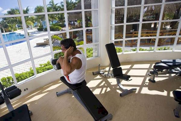 Fitnessstudio im Hotel Catalonia Royal Tulum mit Blick auf den Pool.