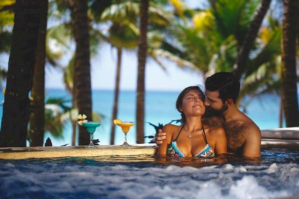 Paar im Pool beim Catalonia Royal Tulum Hotel mit Blick auf den Ozean und Palmen
