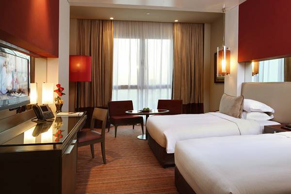 Innenansicht eines Doppelzimmers im Park Rotana Abu Dhabi Hotel mit zwei Betten, Schreibtisch und Fenstern.
