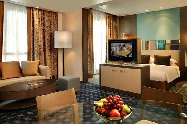 Innenansicht der Suite im Park Rotana Abu Dhabi Hotel mit Wohnzimmer, Couch, Tisch, Fernseher und Essbereich.